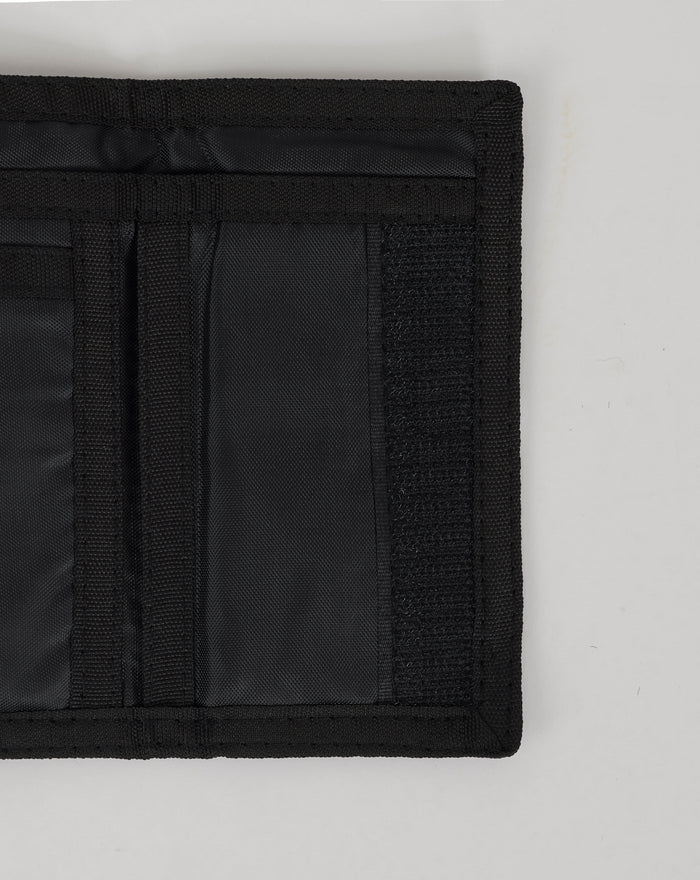Close up of the wallet edge in black fabric showing reinforced stitching and webbing strap