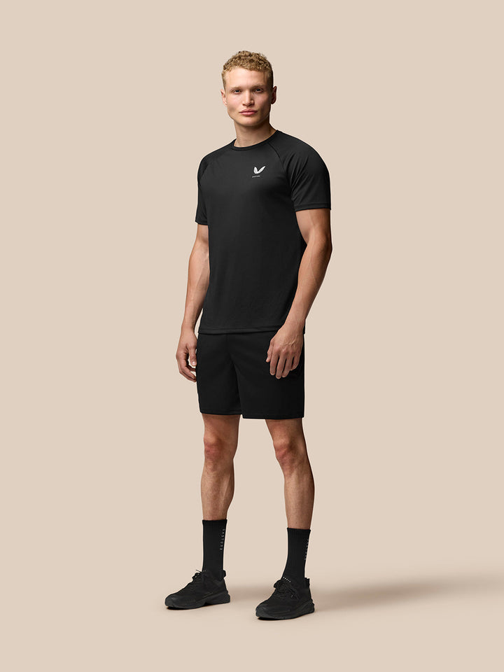 Male model wearing black Adapt Training seven-inch shorts with a matching top against a beige backdrop.