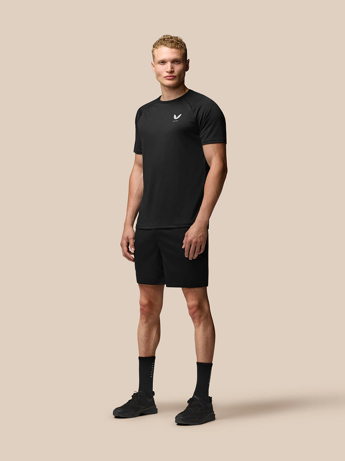 Male model wearing black Adapt Training seven-inch shorts with a matching top against a beige backdrop.