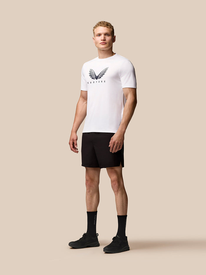 Full-body front view of male model in white Adapt Training T-Shirt with wings logo and black shorts.