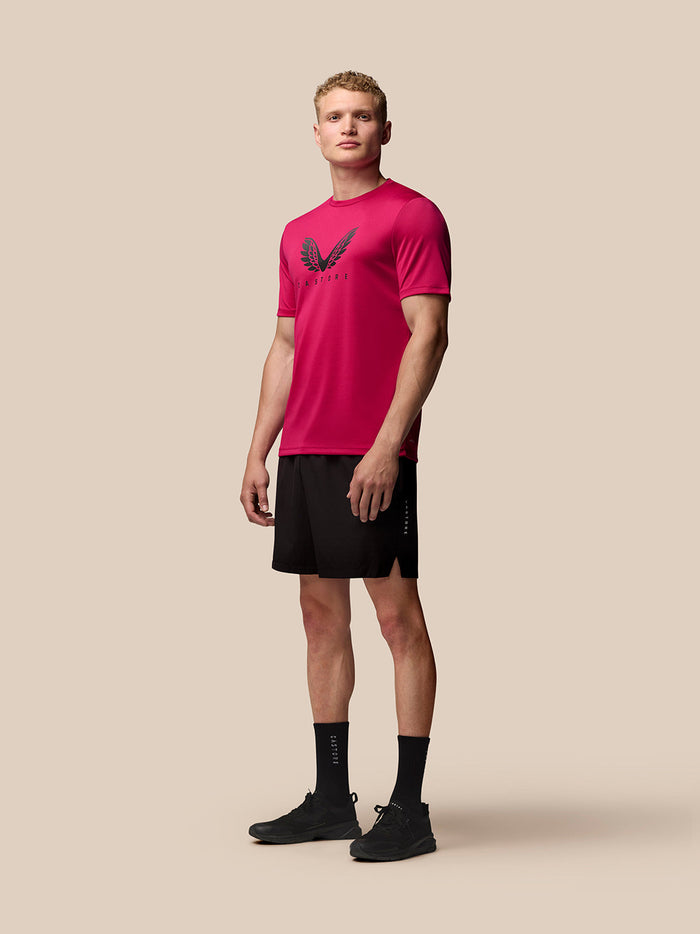Full-body front view of a man wearing pink Adapt Training T Shirt with a wings graphic and black shorts