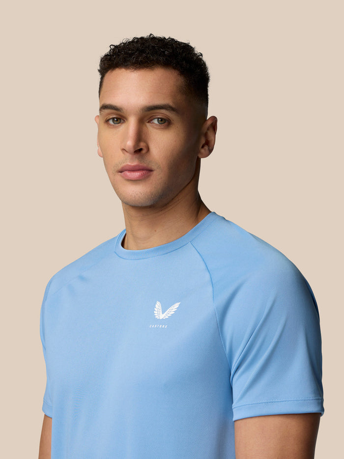 Three-quarter front view of a man in sky blue Adapt Training T-Shirt showing Castore logo on the left chest