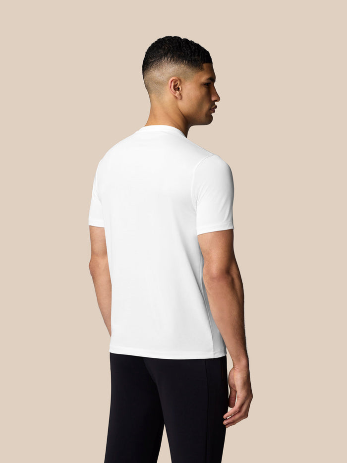 Back view of a man wearing a white graphic training T-shirt against a beige background