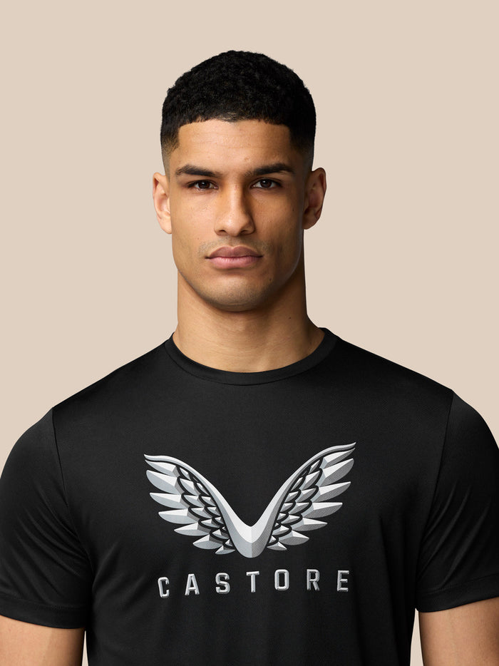 Close-up of black graphic T shirt chest showing the silver wing Castore logo.