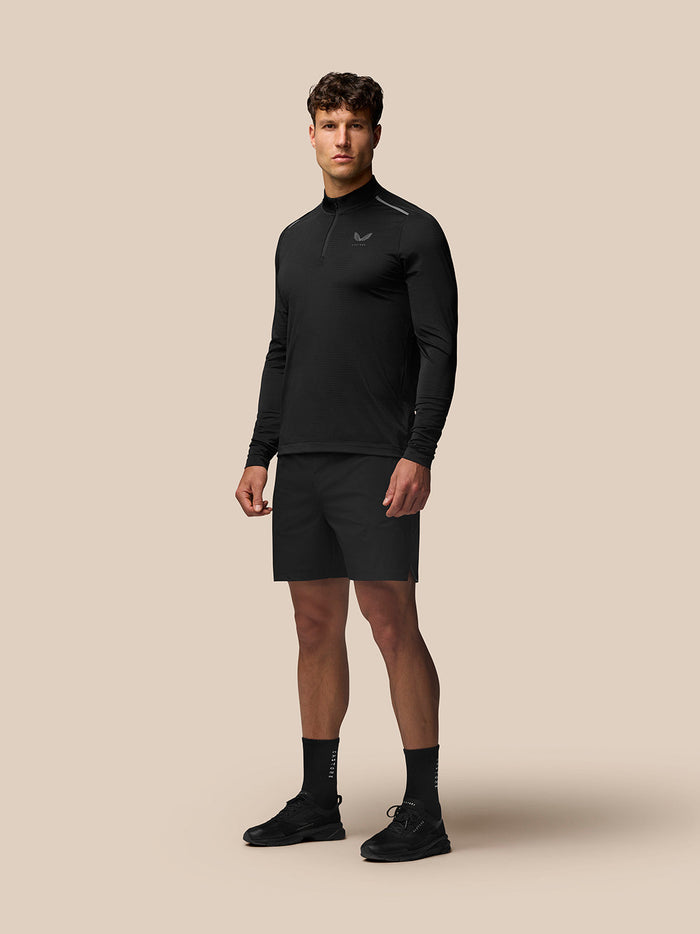 Full-body view of a male model in the black Apex Training Quarter Zip Top with stand collar and black shorts