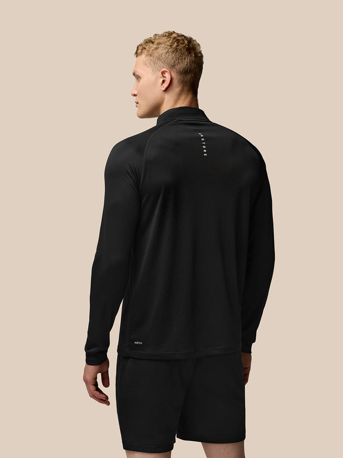 Back view of male model wearing black Adapt Training Quarter Zip Top with long sleeves and Aertek branding at lower left back