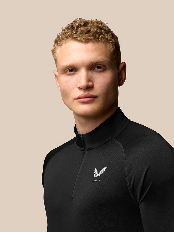 Model wearing black Adapt Training Quarter Zip Top with stand collar and chest Castore logo