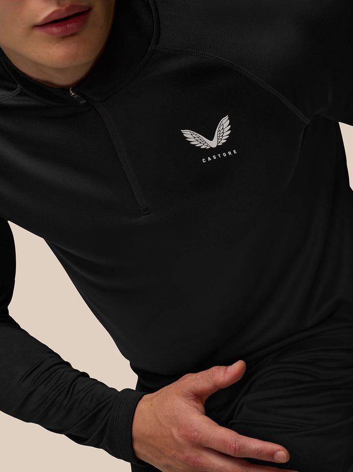 Close up of black Adapt Training Quarter Zip Top with white Castore wing logo on chest