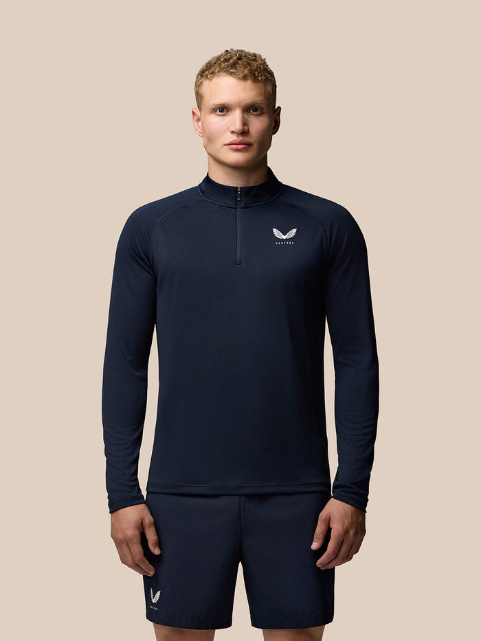 Model wearing midnight navy Adapt Training Quarter Zip Top with stand collar and Castore logo on the left chest