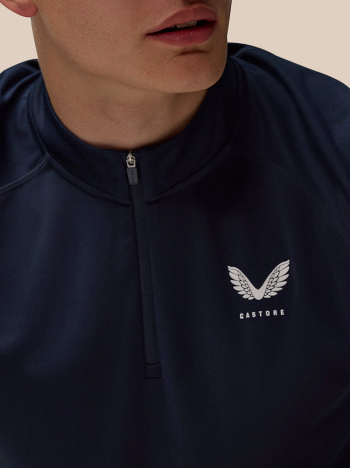Close up of navy Adapt Training Quarter Zip Top showing center zip and Castore logo on left chest.