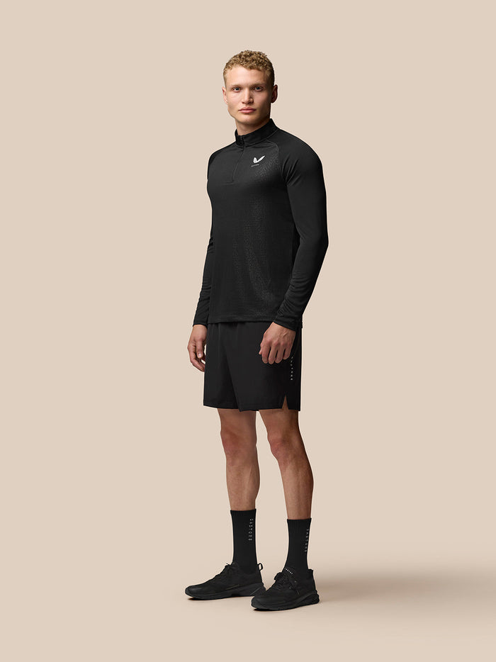 Front view of a male model in black Adapt athletic top and shorts, featuring geometric texture and Castore logo on the chest.