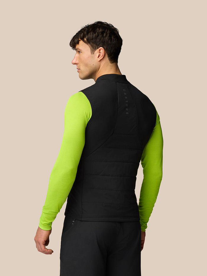 Back view of a model wearing the Apex Training Gilet in black with neon lime sleeves and Castore branding along the spine.