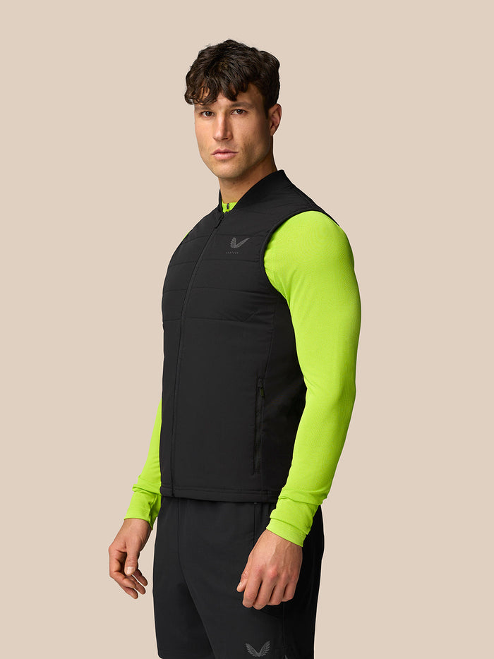 Side view of a man wearing a black Apex Training Gilet over a neon green long-sleeve top