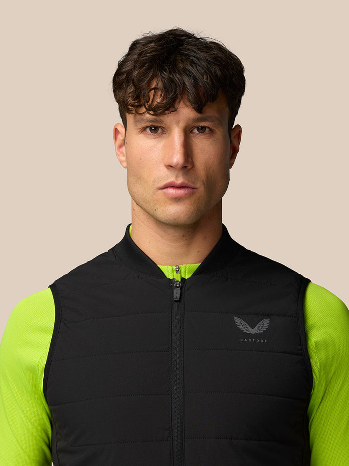 Front view of a man wearing the Apex Training Gilet in black with neon lime sleeves and a Castore crest on the chest.