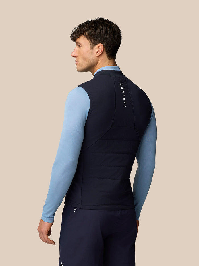 Rear view of male model wearing navy Apex Training Gilet with vertical CASTORE branding on the back.
