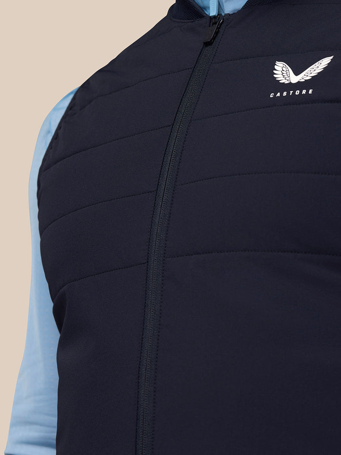 Close-up of navy Apex Training Gilet front showing central zipper and Castore logo on the left chest.