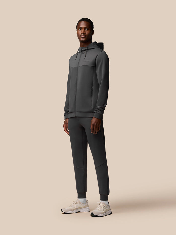 Full-body front view of a man wearing charcoal Flex Lifestyle Joggers and matching zip hoodie.