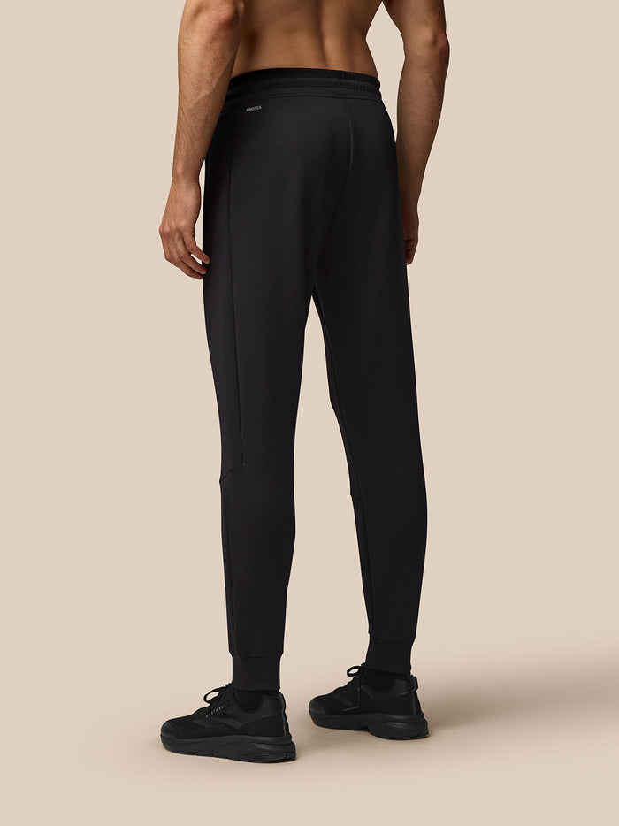 Back view of a man in black Flex Lifestyle Joggers showing a tapered leg and elastic waistband
