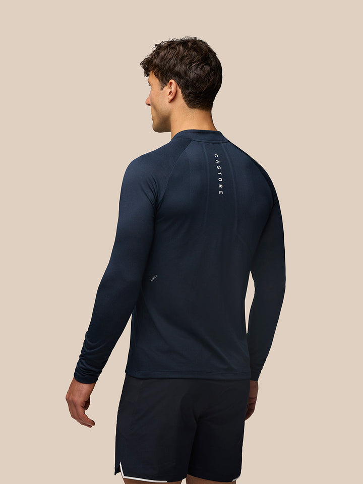 Back view of midnight navy Apex Long Sleeve Engineered Knit Quarter Zip Top with vertical Castore branding along the back