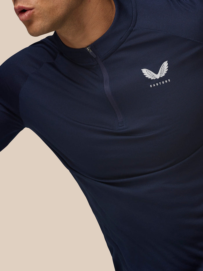 Close-up of Midnight Navy Apex Training Quarter Zip Top on a model showing stand collar and left chest Castore logo