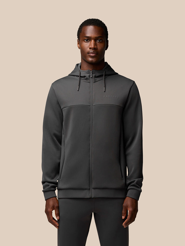 Man wearing charcoal Flex Lifestyle Full Zip jacket with hood and front zip, Castore branding on chest.