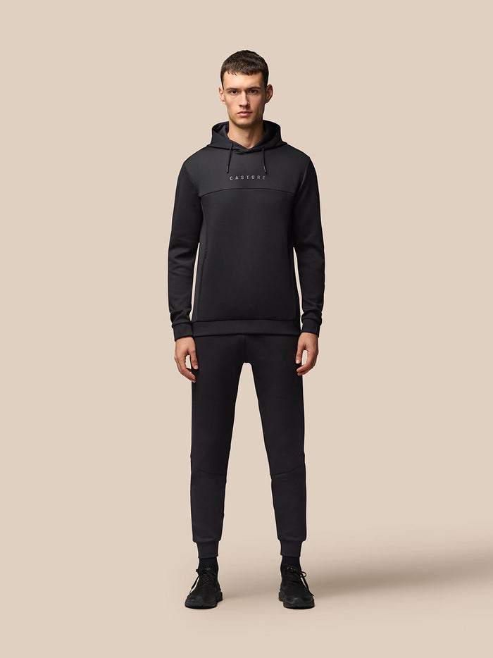 Full body view of male model in black Flex Hoodie and matching joggers, hood up.