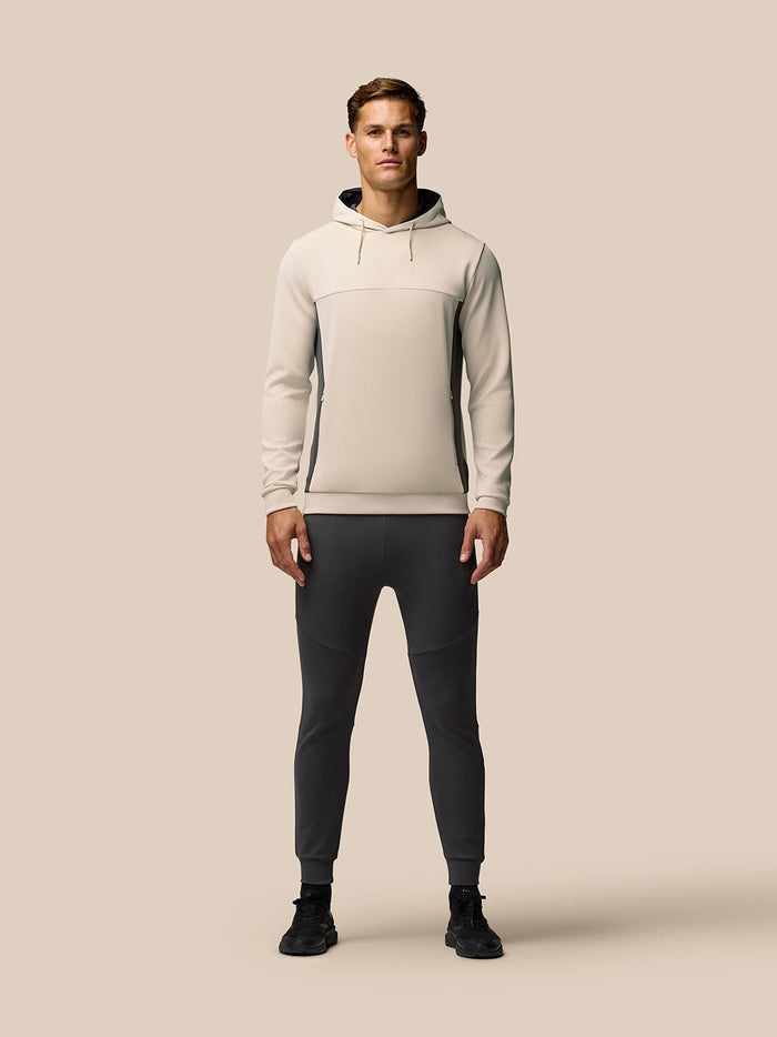 Male model wearing beige Flex Lifestyle hoodie with dark side panels and a drawstring hood.