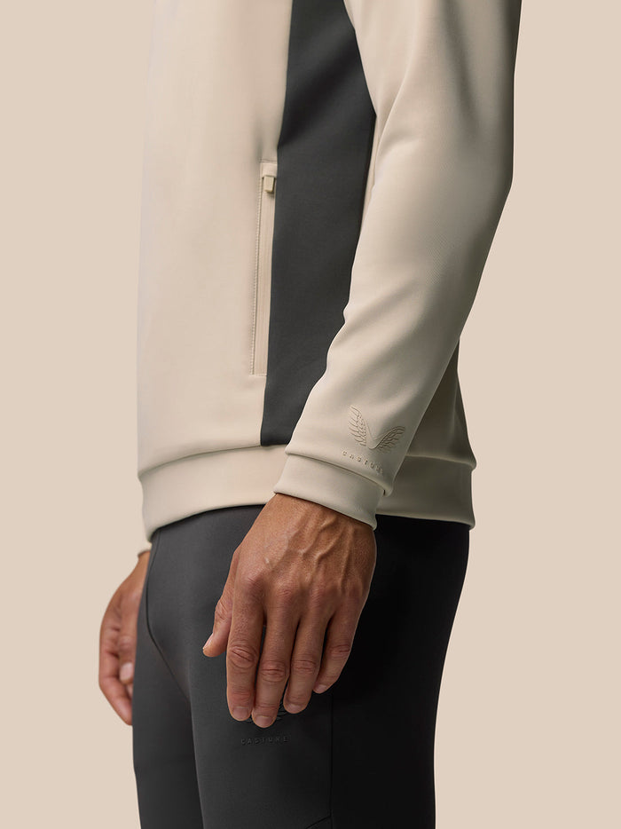 Close up of beige hoodie sleeve with contrasting panel and embossed Castore logo at the cuff