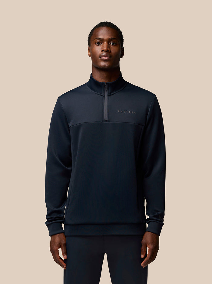 Male model in navy Flex Quarter Zip top with a zip at the neck and Castore branding on the chest