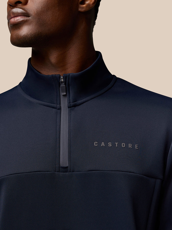 Close-up of the navy Flex Lifestyle Quarter Zip top showing a front zipper and Castore branding on the chest.