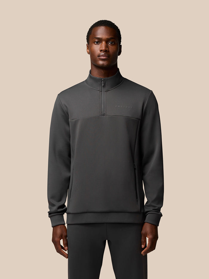 Front view of a male model wearing charcoal Flex 1/4 Zip Sweatshirt with high collar and Castore branding