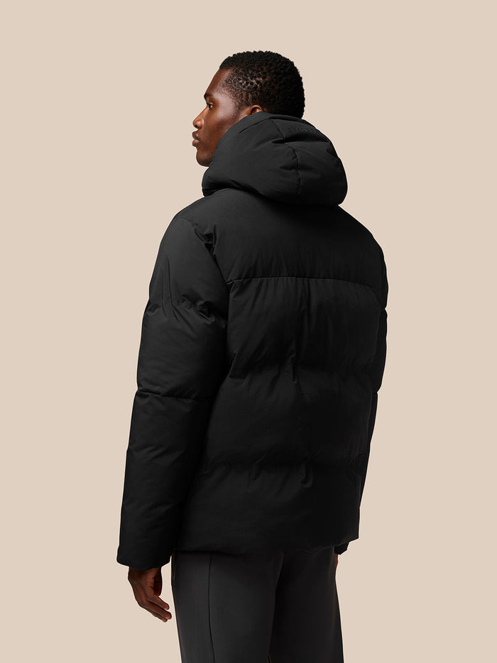 Back view of black hooded puffer jacket on male model
