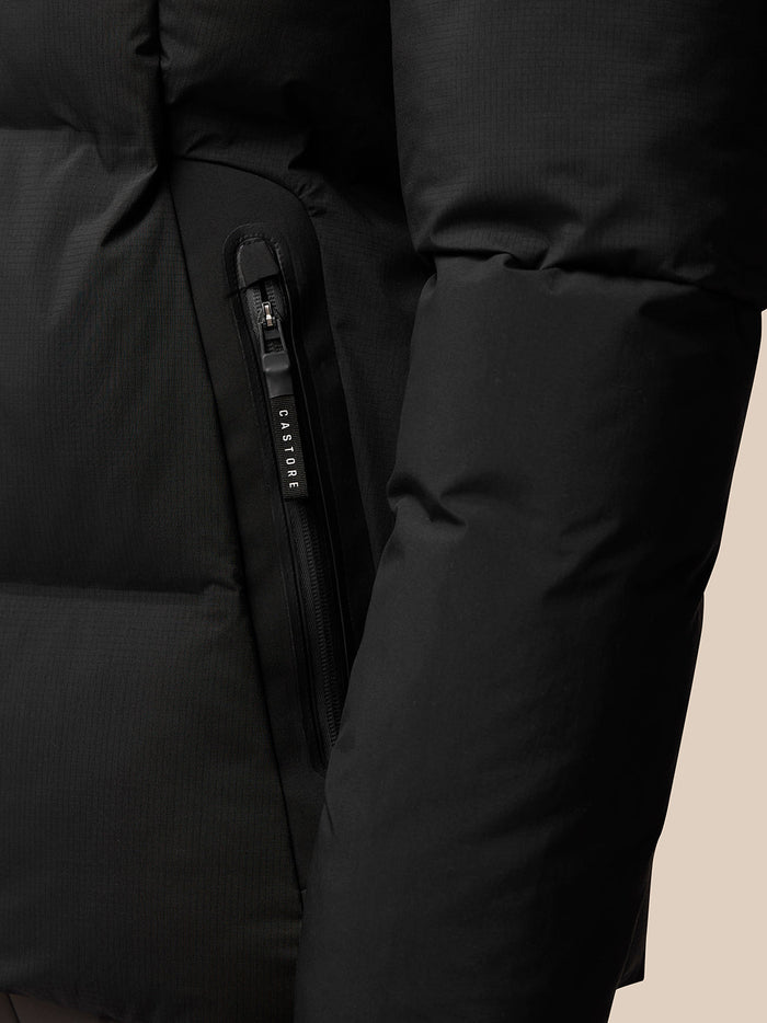 Close-up of black puffer jacket side pocket zip with CASTORE branded pull