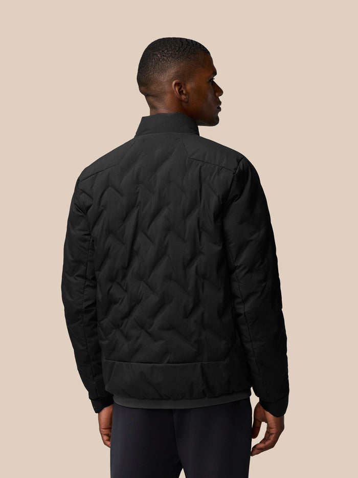 Back view of black padded jacket on a male model showing quilted chevron stitching and ribbed hem.