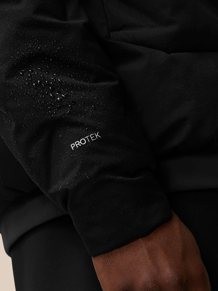 Close-up detail of the sleeve with Protek branding and water droplets on the fabric.