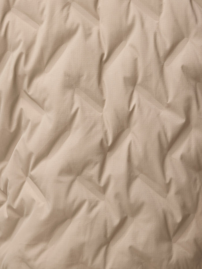 Close-up of mushroom padded jacket fabric showing a subtle grid texture