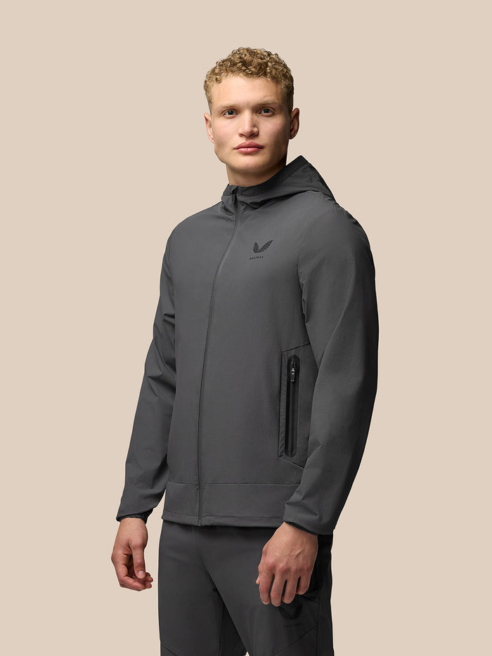 Male model wearing charcoal Lightweight Flex Jacket with hood and front zip