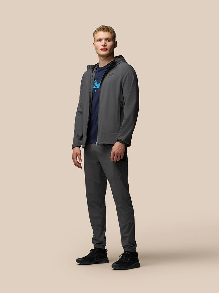 Full-body view of a male model wearing a charcoal Flex Jacket set with hood and matching pants.