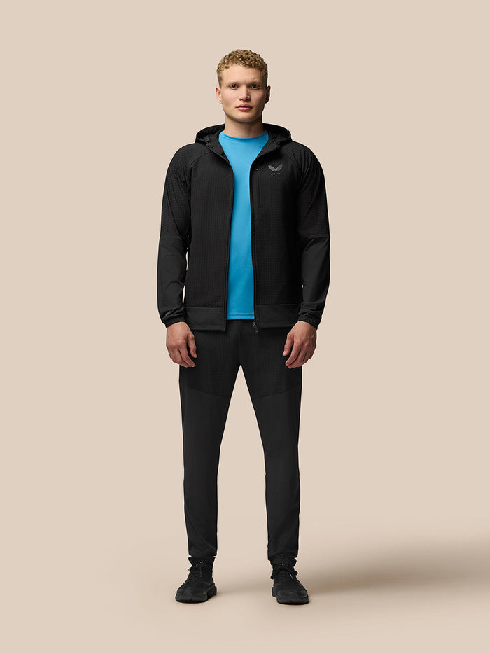 Male model wearing black Flex Winterised Jacket with hood and full zip, blue top peeking through.