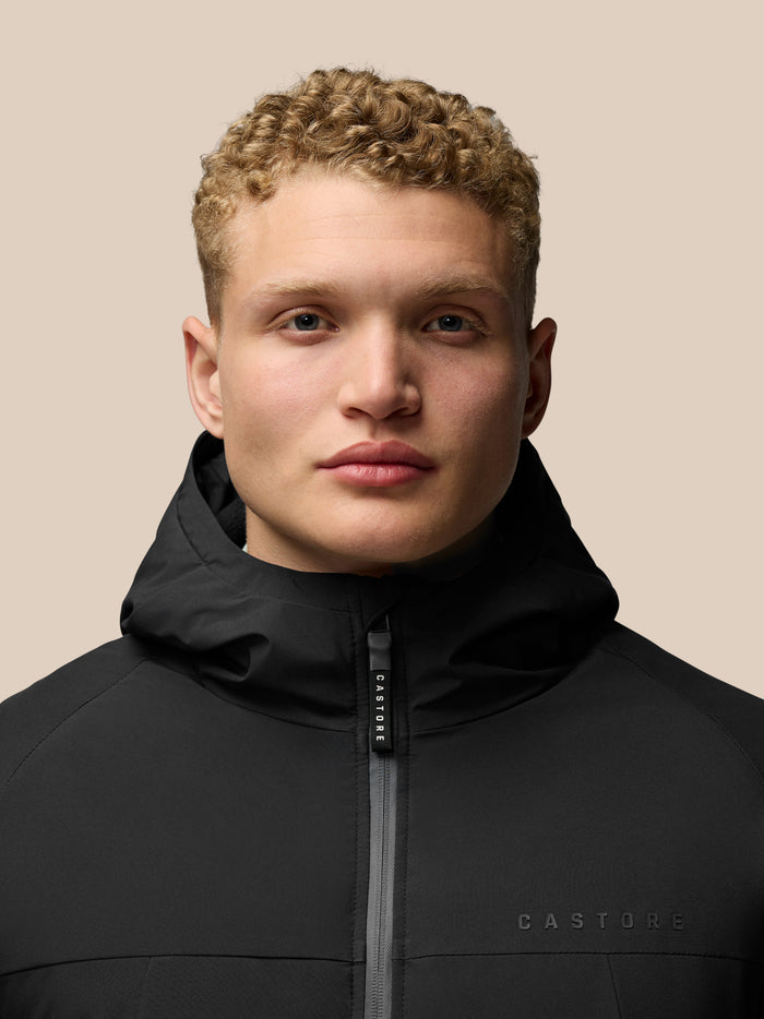 Close up of model wearing black hooded longline wadded jacket with high collar