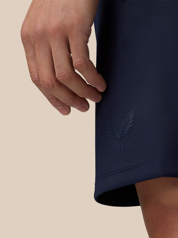 Close-up of navy fabric with embossed Castore wing logo near the hem