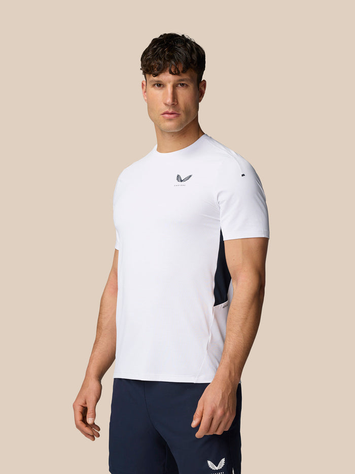 Male model wearing white Apex Training T-Shirt with navy side panels and navy shorts.