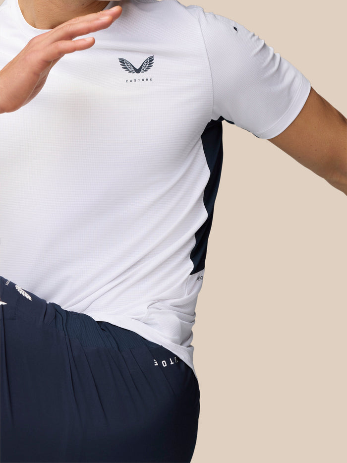 Three quarter view of a model in white Apex Training T-Shirt showing the Castore logo on the chest and navy side panels.