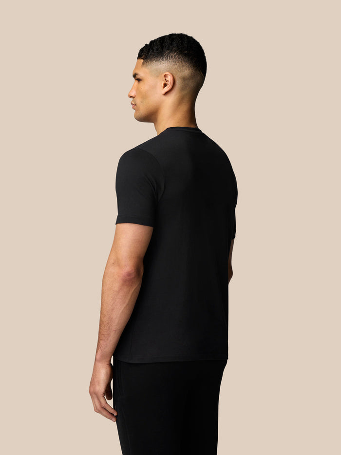 Back view of man in black short sleeve Castore T shirt against a beige backdrop