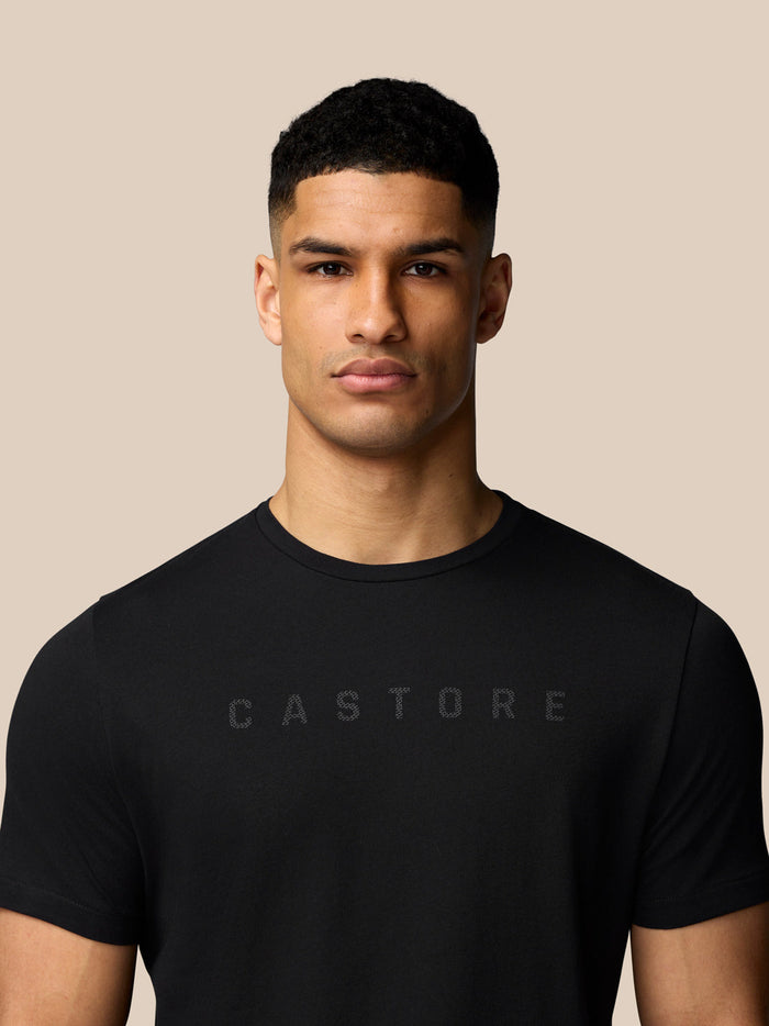 Male model wearing black Castore graphic T shirt with crew neck and short sleeves.