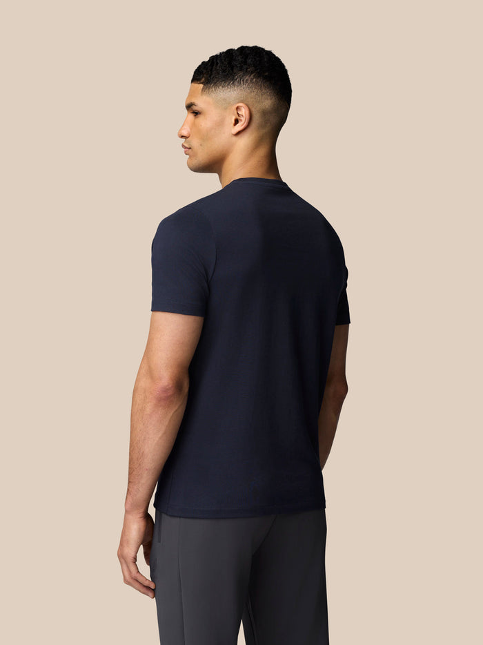 Back view of male model in navy Castore graphic T shirt with drop shoulder fit