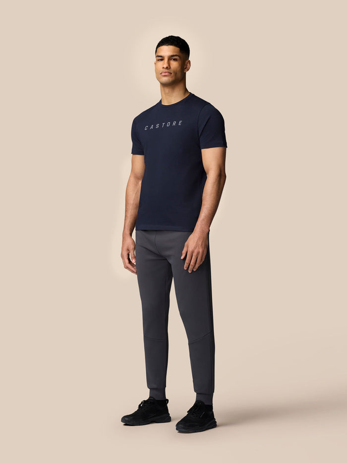 Rear three-quarter view of male model in navy Castore graphic T shirt showing relaxed fit