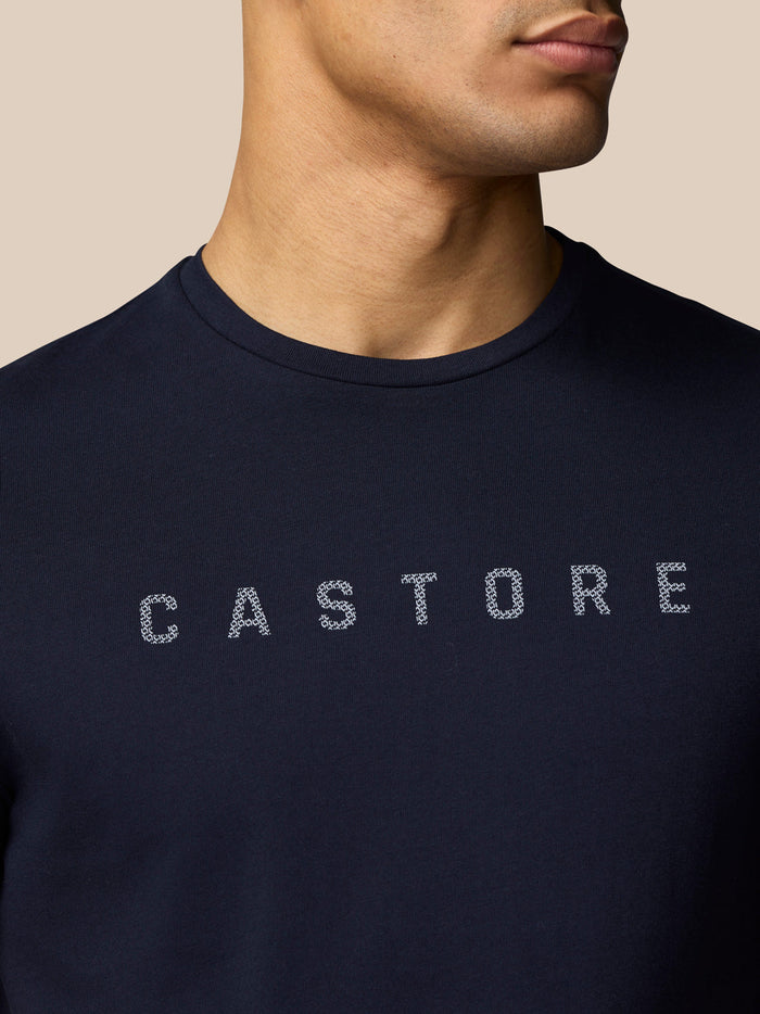 Detail shot of navy T-shirt featuring CASTORE graphic with dotted lettering across the chest.
