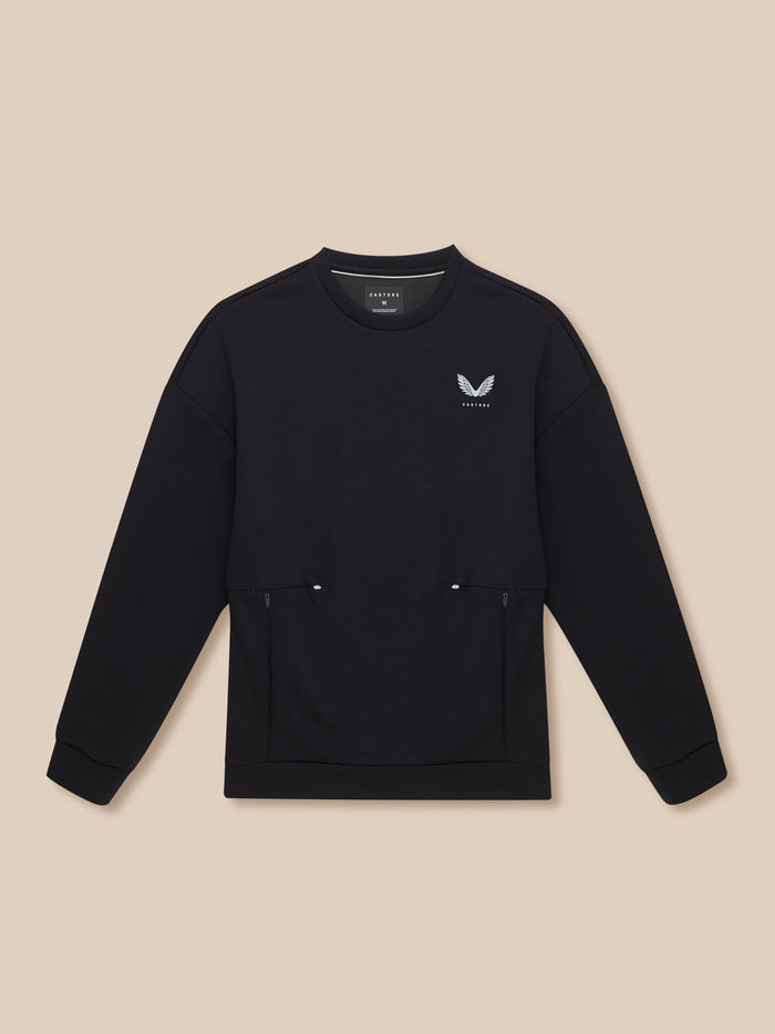 Flat lay of black Travel Lifestyle Sweatshirt on beige background with white wing logo and front zip pockets