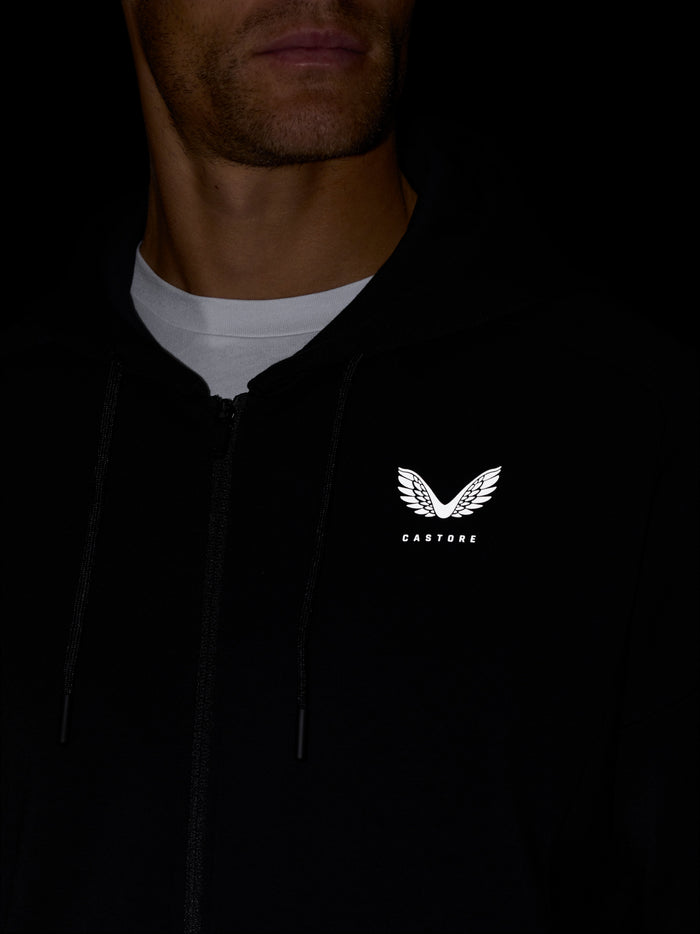 Close-up of a man wearing the black Travel Zip Hoodie with a visible chest Castore logo and zip detail.